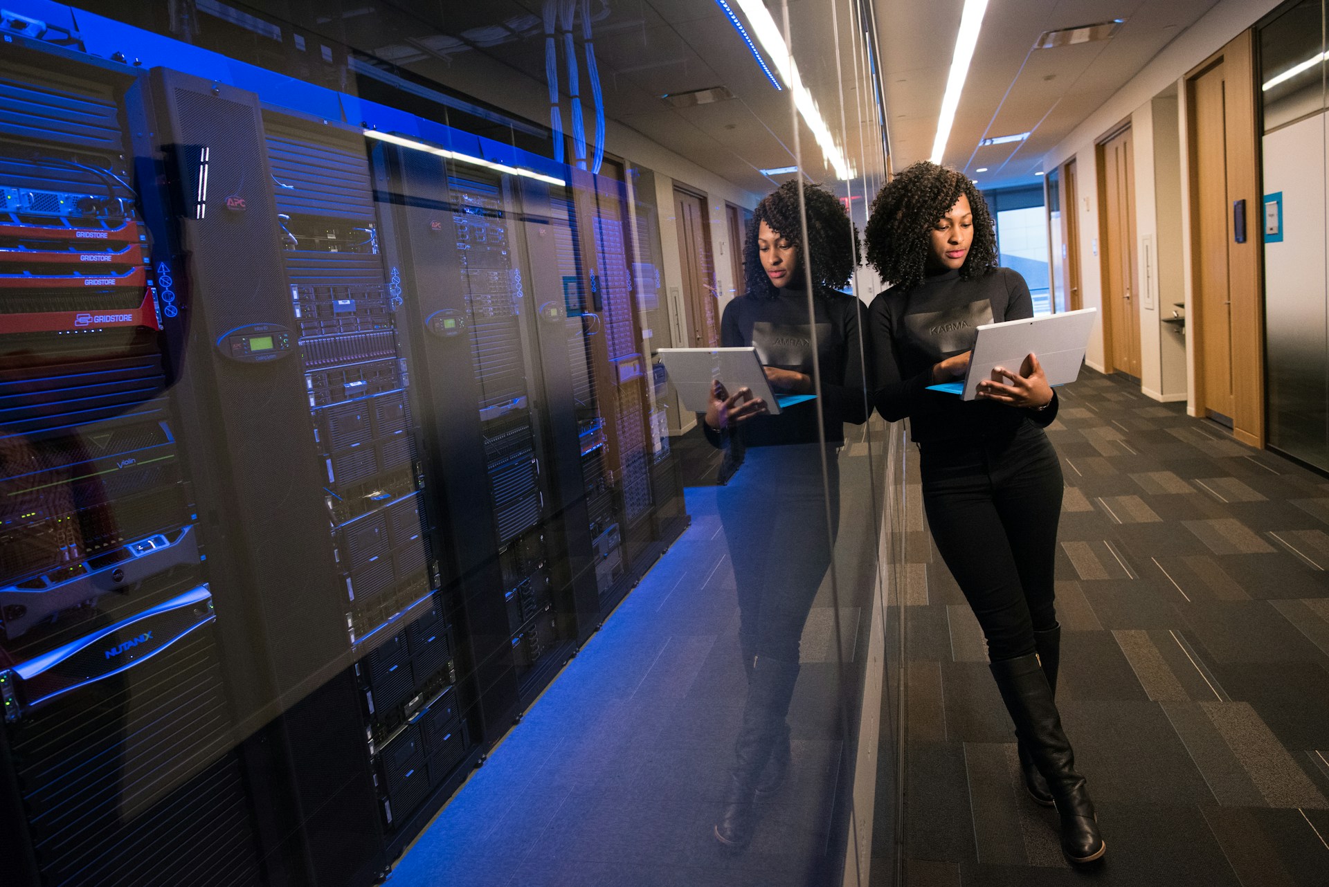 A woman in a black shirt and black boots is holding a tablet computer.